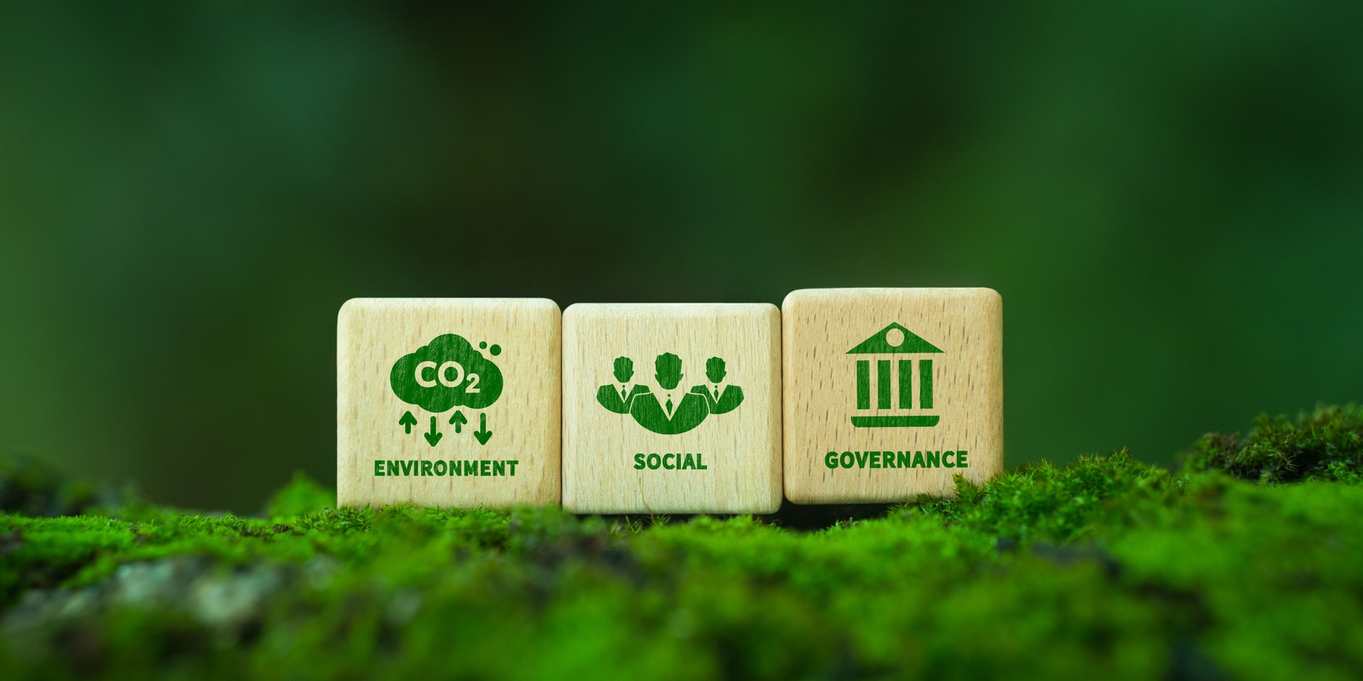 Green ESG icon on wooden block. Environment, social and governance concept. Net zero greenhouse gas emissions for a sustainable global environment. On a green forest background.